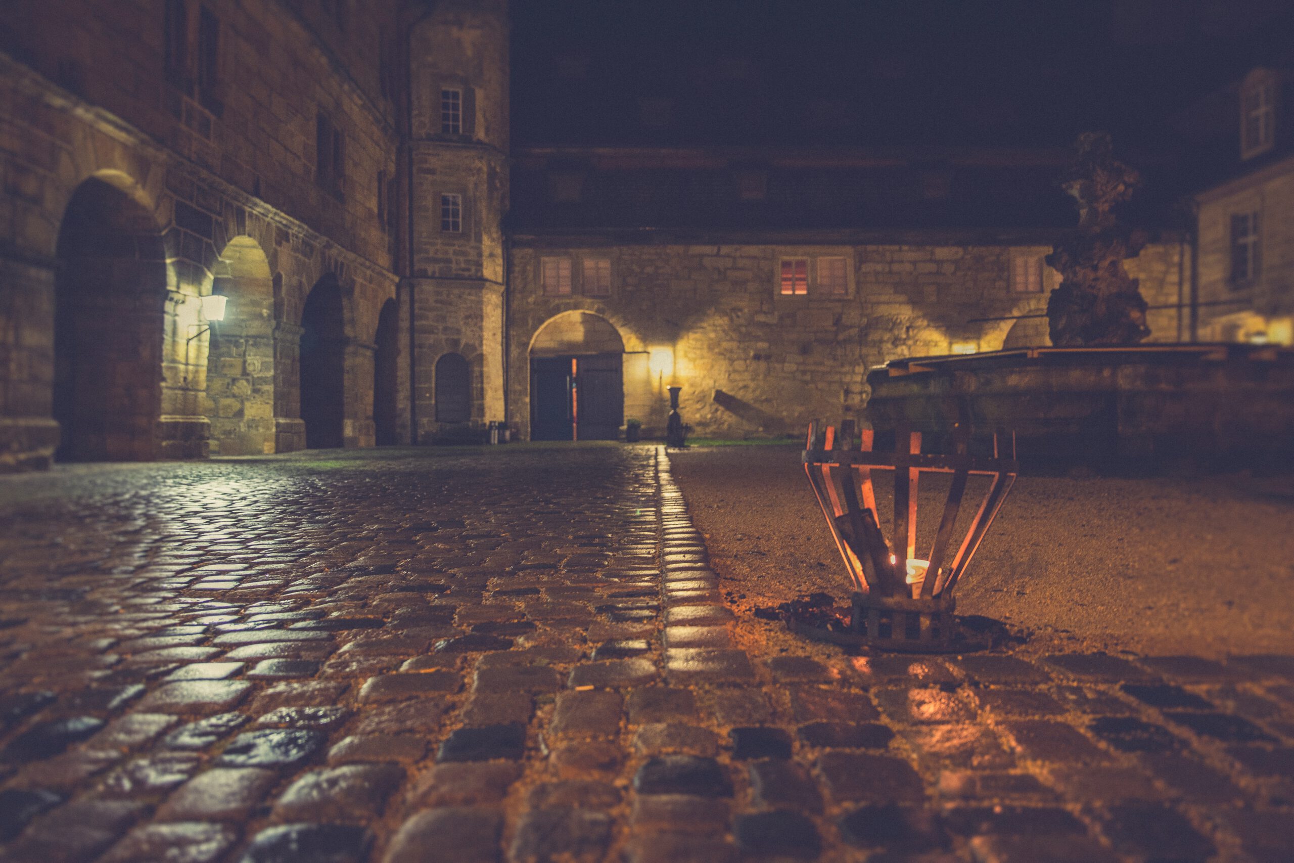 Dziedziniec zamku nocą z palącą się świecą